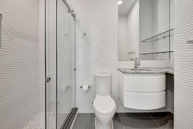 bathroom with vanity, toilet, tile floors, and a shower with door