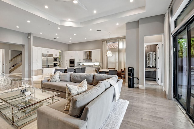 living room with an inviting chandelier, light hardwood / wood-style flooring, and a tray ceiling