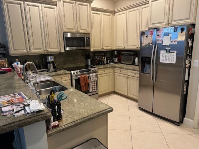 kitchen with dark stone counters, sink, light tile flooring, and appliances with stainless steel finishes