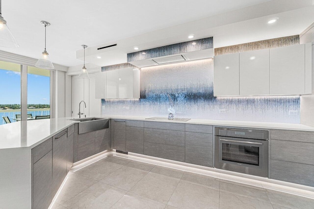 kitchen with sink, hanging light fixtures, stainless steel oven, a water view, and black electric cooktop