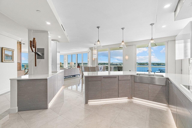 kitchen with light tile patterned flooring, sink, hanging light fixtures, a water view, and a spacious island