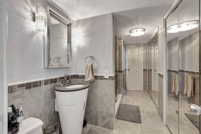 bathroom with vanity, toilet, and tile walls