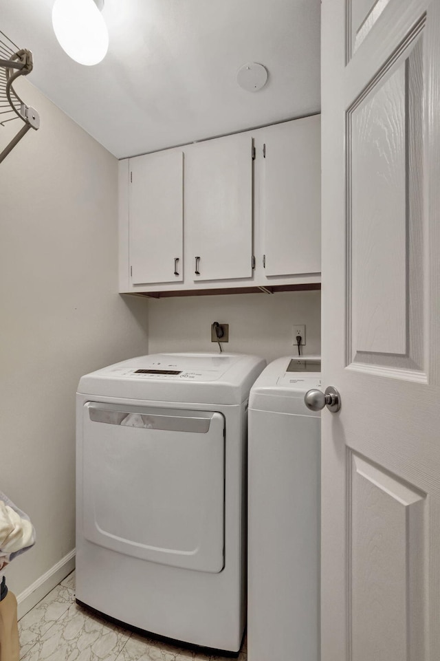 clothes washing area featuring cabinets and separate washer and dryer