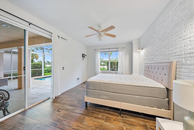 bedroom featuring ceiling fan, access to exterior, dark hardwood / wood-style flooring, and brick wall