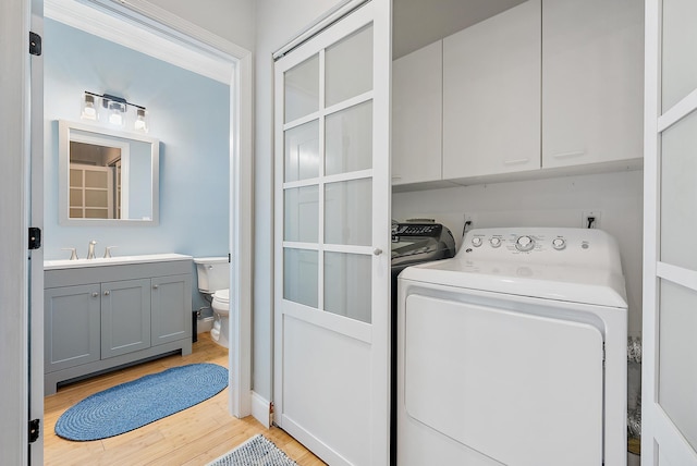 clothes washing area featuring cabinets, light hardwood / wood-style flooring, sink, and independent washer and dryer