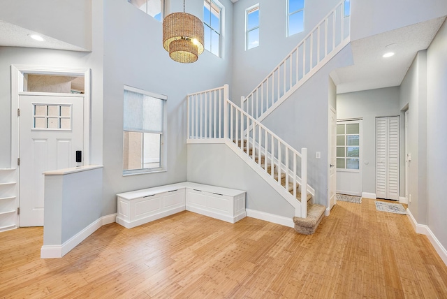 entryway featuring light wood-type flooring, a wealth of natural light, and a high ceiling