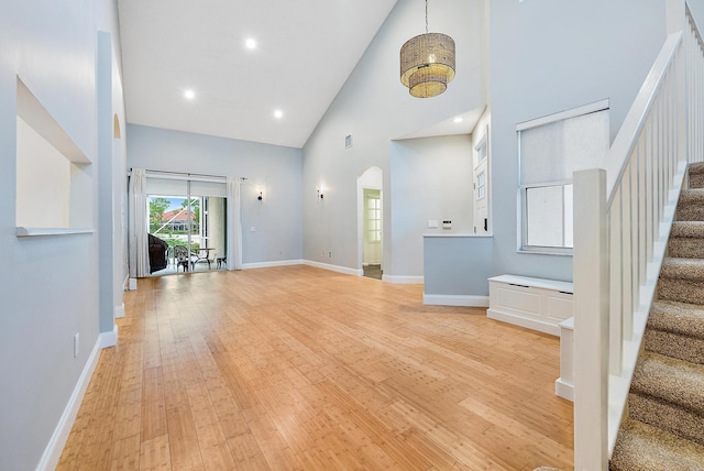 unfurnished living room with high vaulted ceiling and light hardwood / wood-style floors