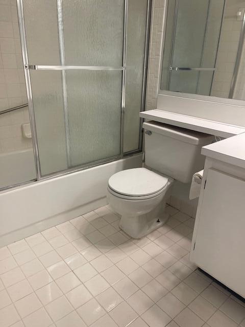 full bathroom with tile patterned flooring, vanity, enclosed tub / shower combo, and toilet