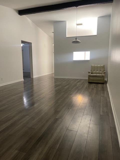 empty room featuring beam ceiling, dark hardwood / wood-style flooring, and high vaulted ceiling