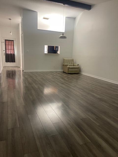 unfurnished living room with beamed ceiling, dark hardwood / wood-style flooring, and high vaulted ceiling