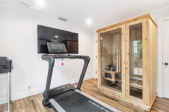 workout area with wood-type flooring and crown molding