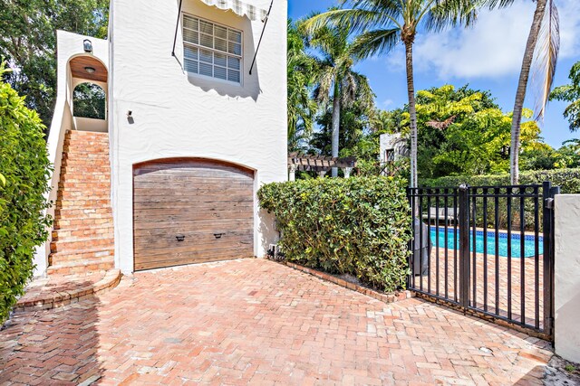 view of patio featuring a fenced in pool and a garage