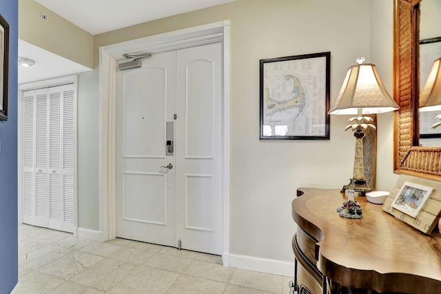 foyer with marble finish floor and baseboards