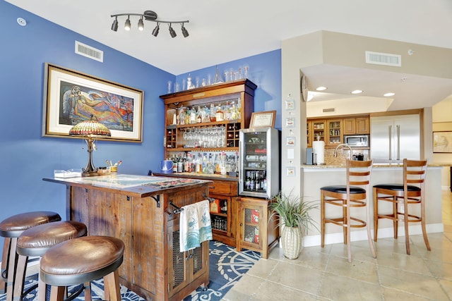 bar featuring backsplash, sink, built in appliances, light tile patterned flooring, and beverage cooler