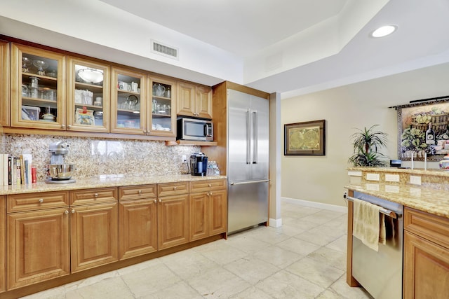 kitchen featuring backsplash, light stone countertops, and appliances with stainless steel finishes