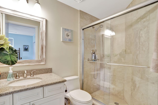 bathroom featuring vanity, a shower with shower door, and toilet