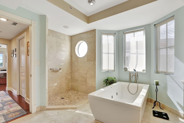 bathroom featuring a freestanding tub, visible vents, a tile shower, and baseboards