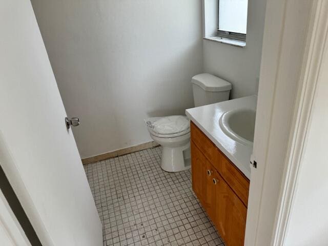 bathroom featuring tile flooring, toilet, and vanity