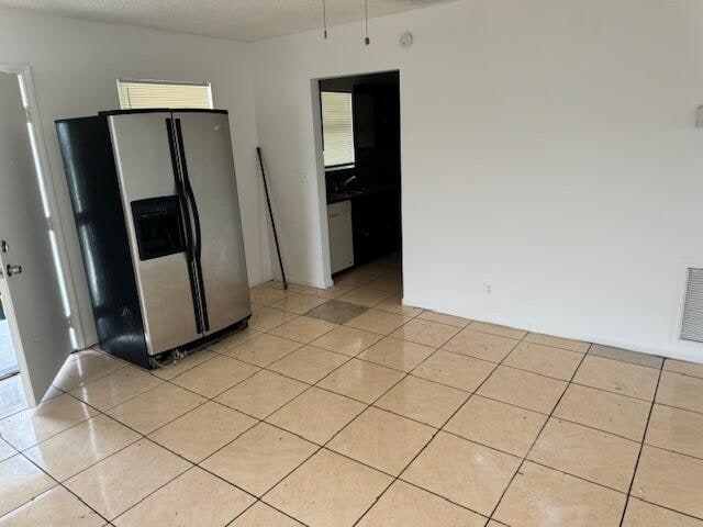 kitchen with light tile flooring and stainless steel refrigerator with ice dispenser