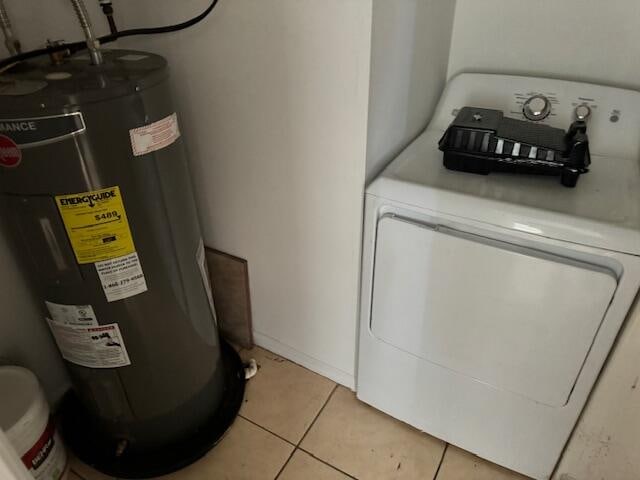 clothes washing area with light tile flooring, washer / clothes dryer, and water heater