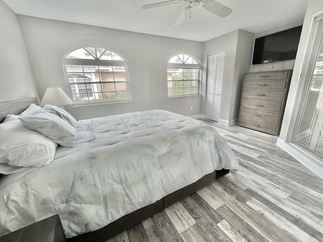 bedroom featuring a textured ceiling, light wood-type flooring, a closet, and ceiling fan