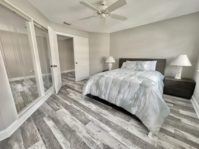 bedroom with ceiling fan, wood-type flooring, and a textured ceiling