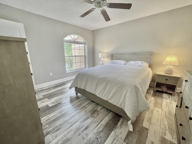 bedroom featuring ceiling fan, light wood-type flooring, and a textured ceiling