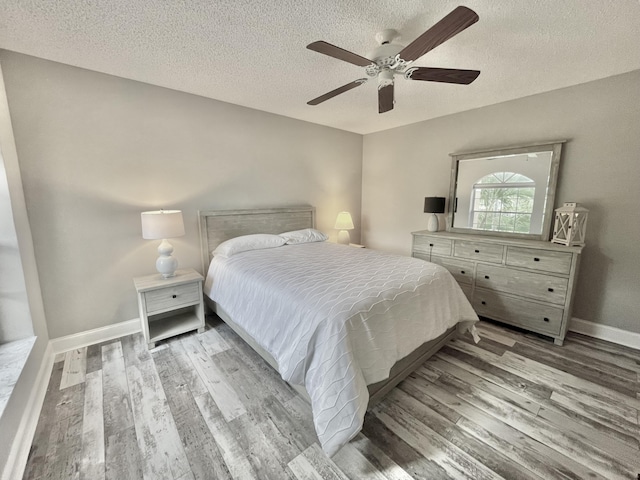 bedroom featuring ceiling fan, light wood-type flooring, and a textured ceiling