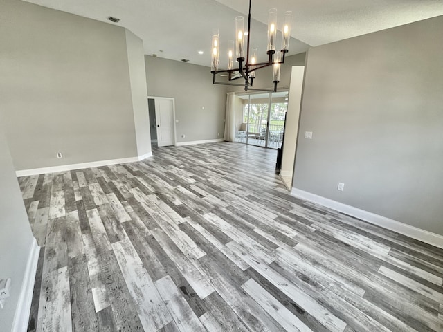 unfurnished dining area with a towering ceiling, a chandelier, and light hardwood / wood-style floors