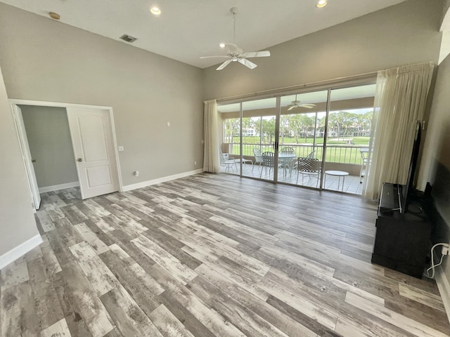 unfurnished living room featuring ceiling fan, light hardwood / wood-style floors, and a high ceiling