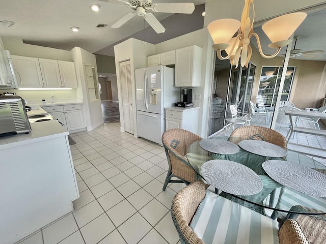 kitchen featuring white cabinetry, white fridge with ice dispenser, light tile patterned floors, and ceiling fan with notable chandelier