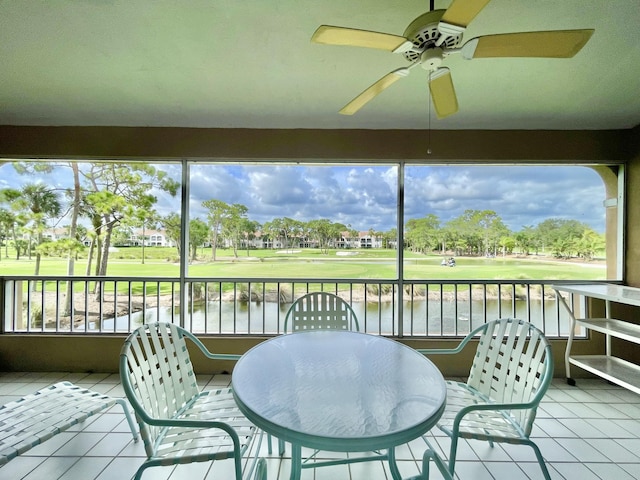 sunroom with ceiling fan and a water view