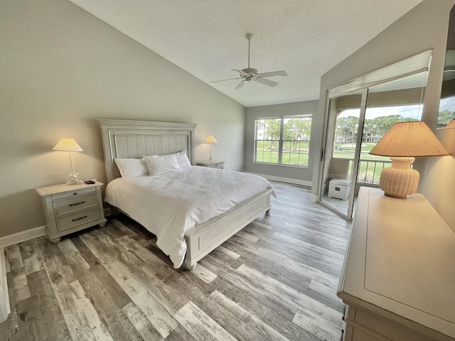 bedroom featuring access to exterior, ceiling fan, vaulted ceiling, a textured ceiling, and hardwood / wood-style flooring