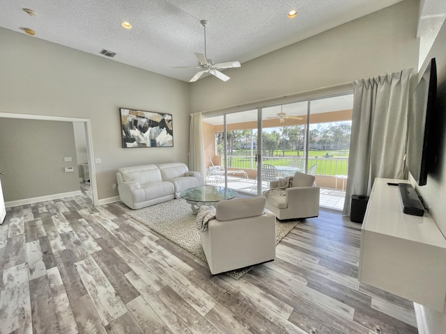 living room with ceiling fan, a textured ceiling, and light hardwood / wood-style flooring