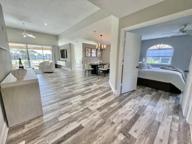 living room featuring hardwood / wood-style flooring, ceiling fan with notable chandelier, and a textured ceiling