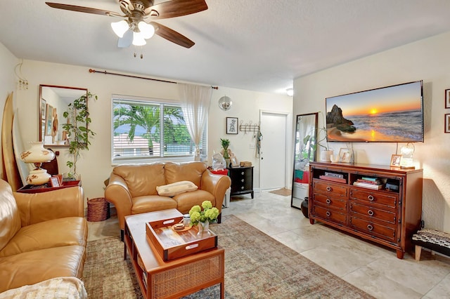 living room with ceiling fan, light tile patterned floors, and a textured ceiling