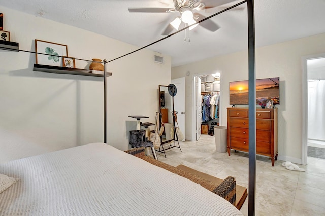 bedroom featuring a textured ceiling, a walk in closet, a closet, and ceiling fan