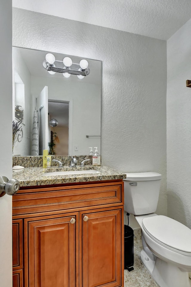 bathroom with vanity, a textured ceiling, and toilet