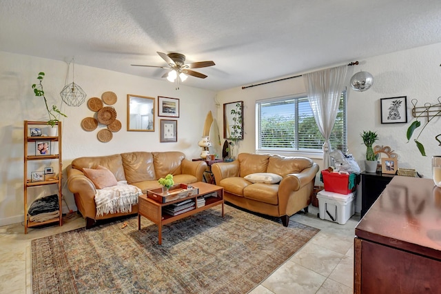 living room with ceiling fan, light tile patterned flooring, and a textured ceiling