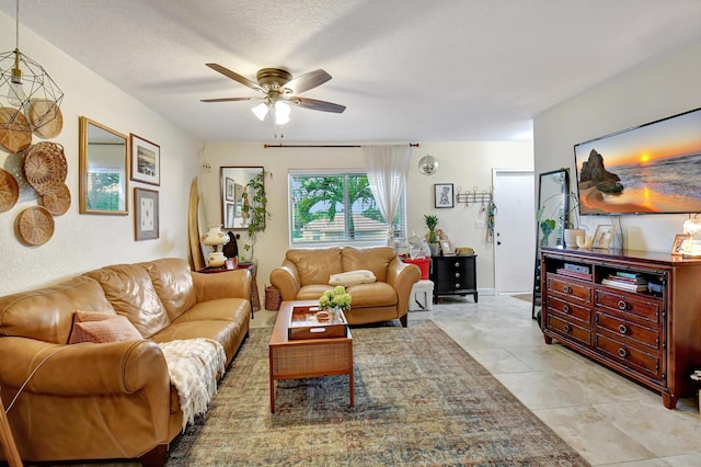 living room with ceiling fan, light tile patterned floors, and a textured ceiling