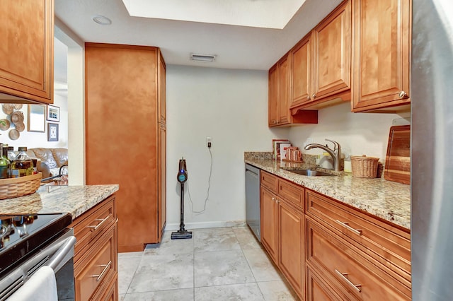 kitchen with light stone countertops, light tile patterned floors, stainless steel appliances, and sink