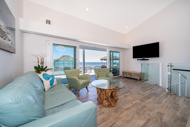 living room featuring high vaulted ceiling, a water view, and hardwood / wood-style floors