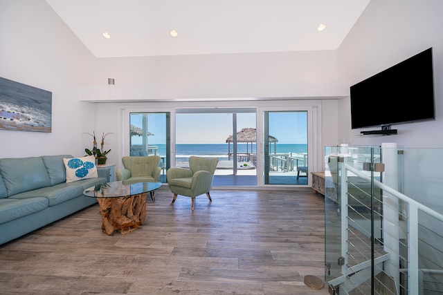 living room featuring high vaulted ceiling, a water view, and hardwood / wood-style floors