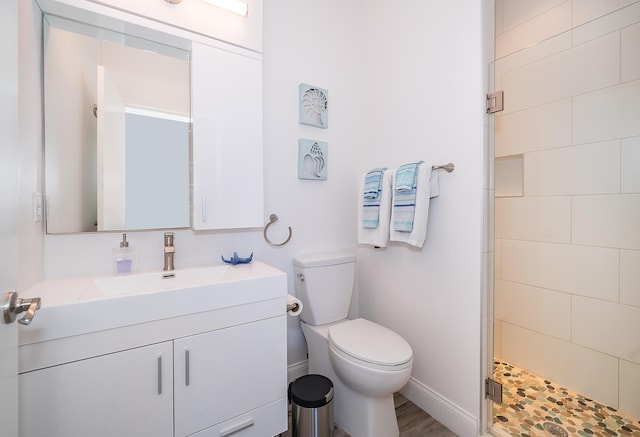 bathroom featuring a tile shower, toilet, and vanity with extensive cabinet space