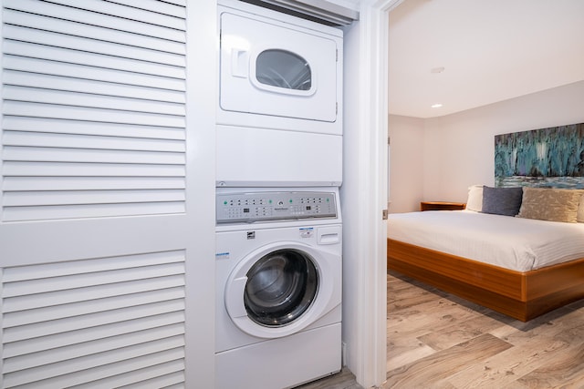 laundry area featuring stacked washing maching and dryer and light hardwood / wood-style floors