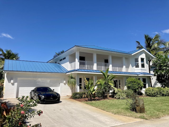 view of front facade with a balcony, a standing seam roof, a garage, and metal roof