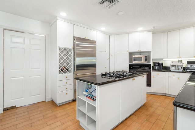 kitchen with white cabinetry, visible vents, stainless steel appliances, and a center island