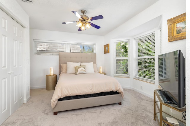 carpeted bedroom featuring ceiling fan, a closet, visible vents, and baseboards