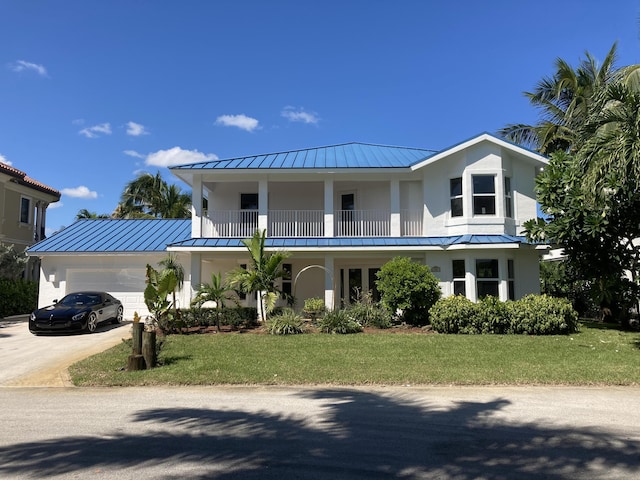 view of front of property featuring a balcony, a front lawn, and a garage