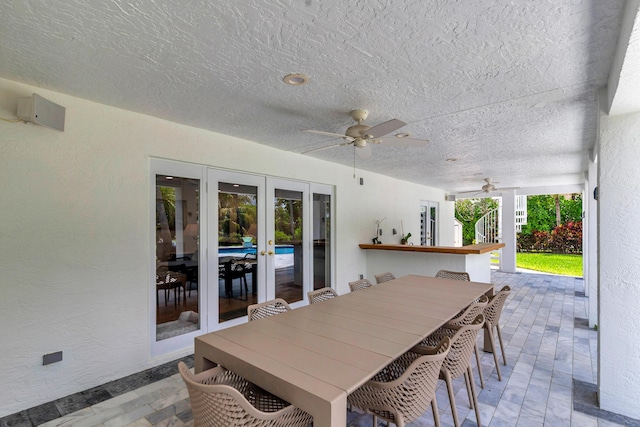 view of patio featuring a ceiling fan, outdoor dining space, french doors, and outdoor dry bar